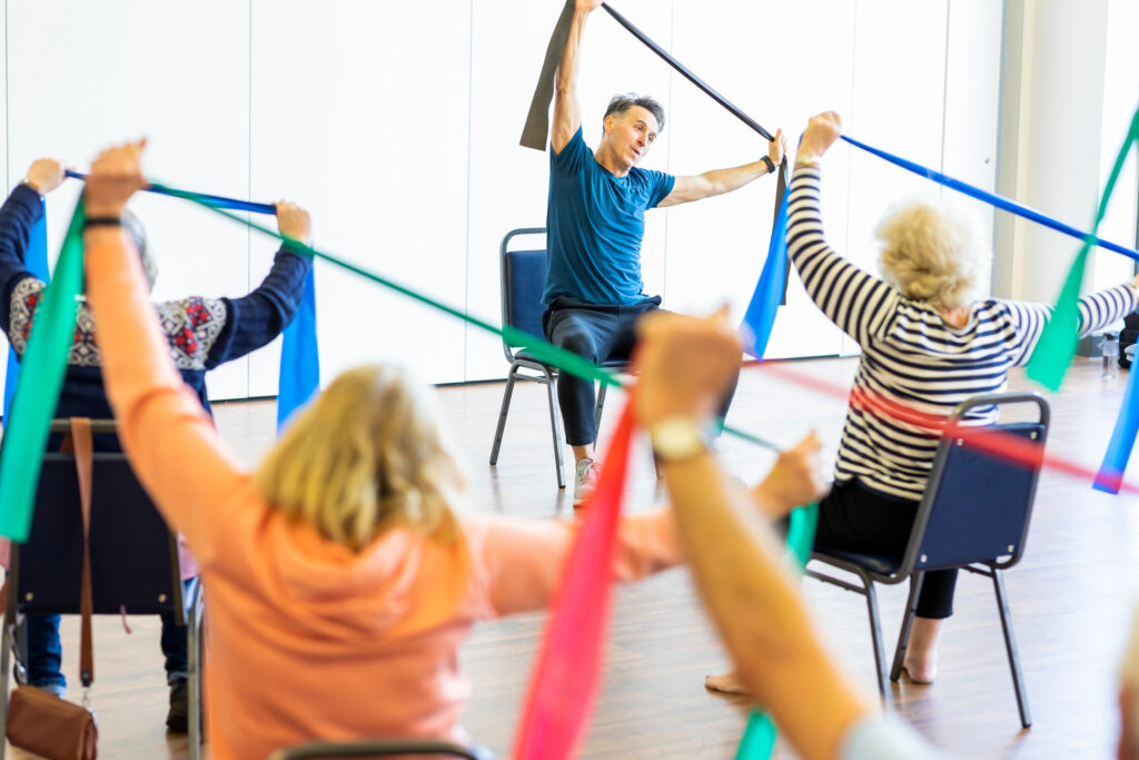 Class of older people use resistance bands to exercise their upper body